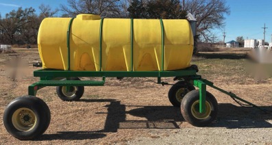 Yellow poly tank strapped to a green flatbed utility trailer