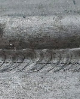 Close-up of a welded steel seam showing stress cracking along the weld